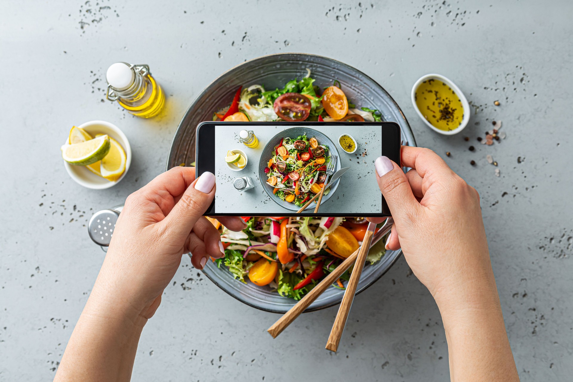 Woman taking photo of vegetable salad with smartphone. Posting food pictures (images) on social media.